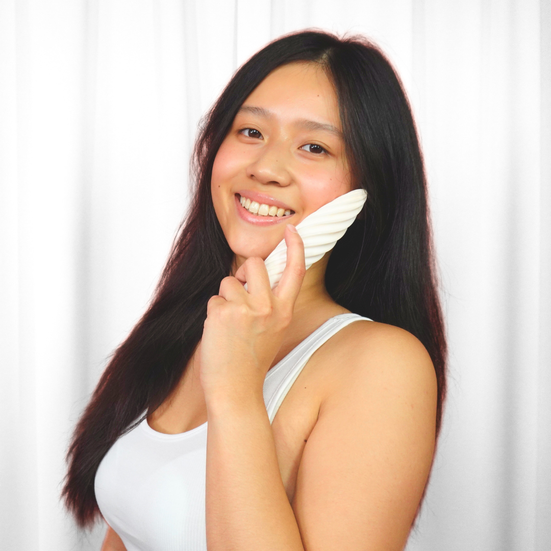 Smiling woman holding the white Fevowell Facer at face level with her left hand during a joyful skincare moment