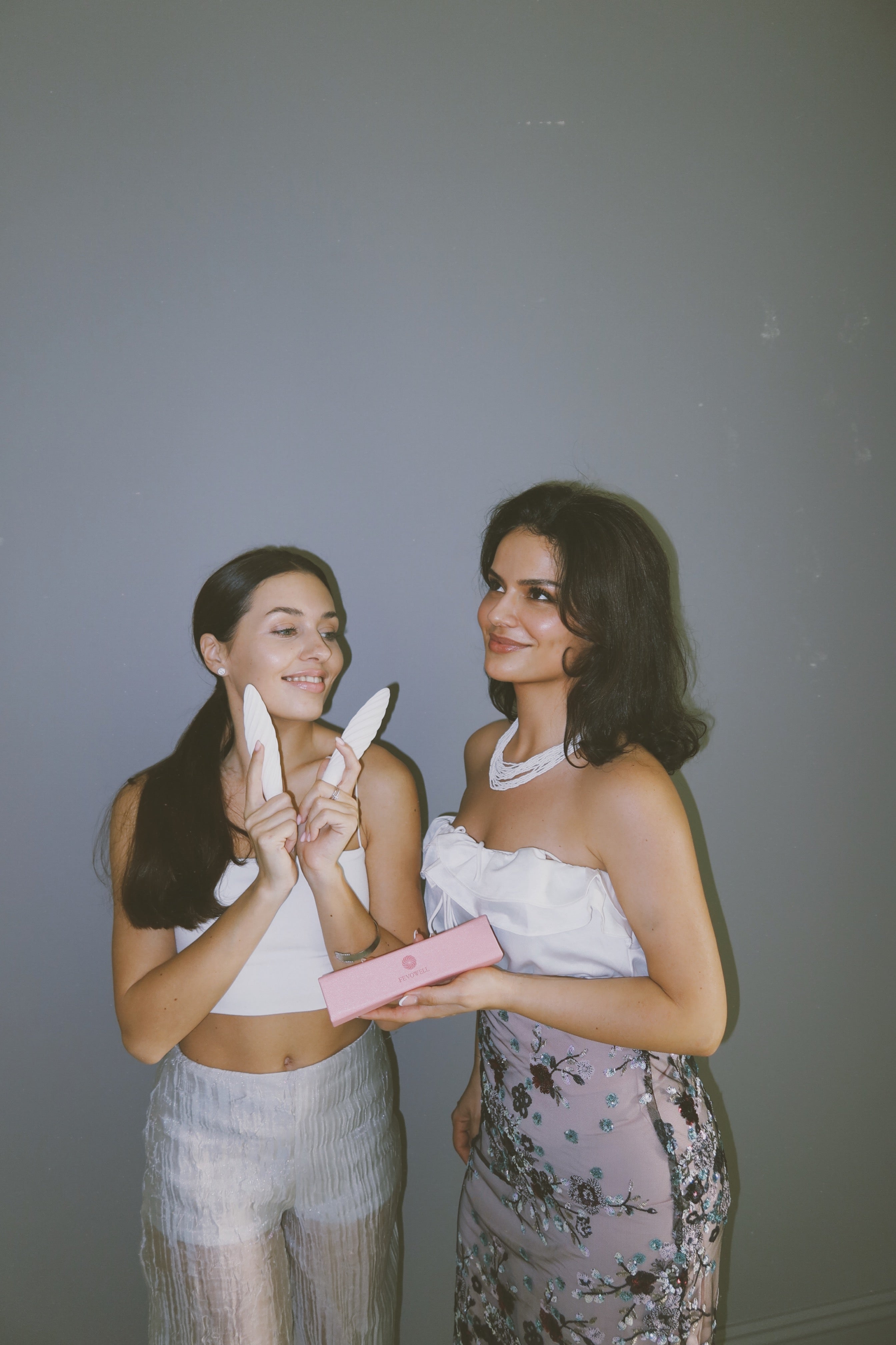 Two smiling women holding the Fevowell Facer beauty tools and gift box, celebrating radiant selfcare moments